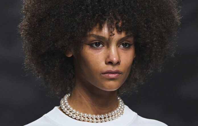 Γυναίκα εφαρμόζει λιπαντικό σε σγουρά μαλλιά